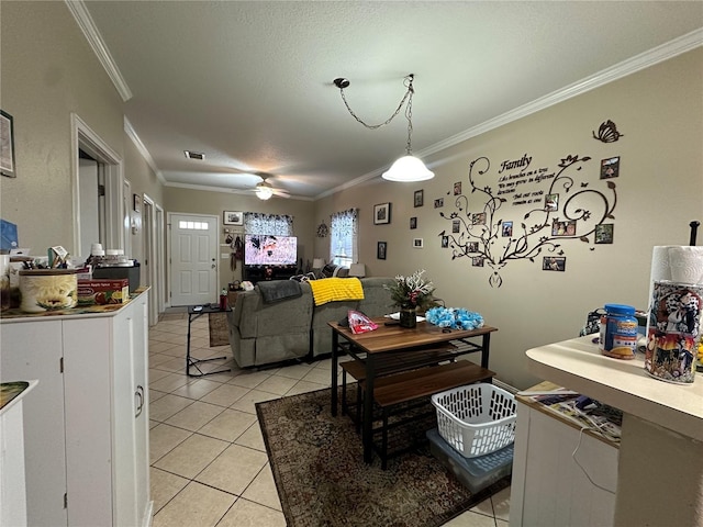 tiled dining area with a textured ceiling, ornamental molding, and ceiling fan