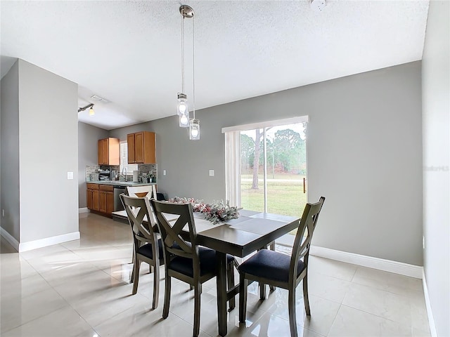 dining space featuring a textured ceiling, light tile patterned floors, and sink