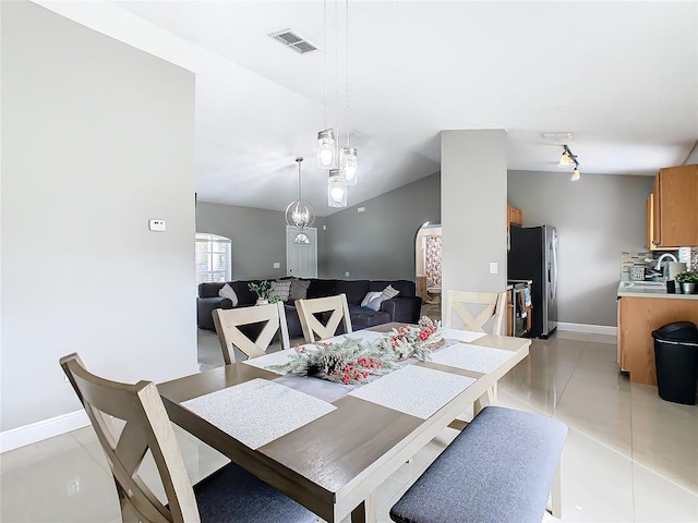 tiled dining space featuring sink and lofted ceiling