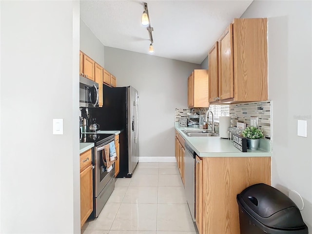 kitchen featuring sink, light tile patterned floors, tasteful backsplash, rail lighting, and appliances with stainless steel finishes