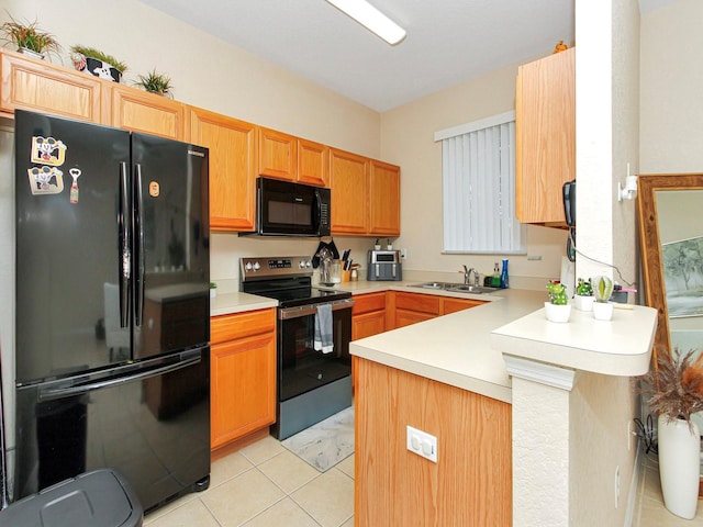 kitchen with sink, light tile patterned floors, black appliances, and kitchen peninsula