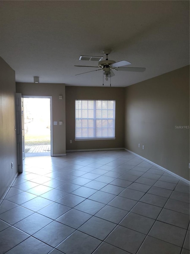 spare room with a healthy amount of sunlight, ceiling fan, and light tile patterned flooring