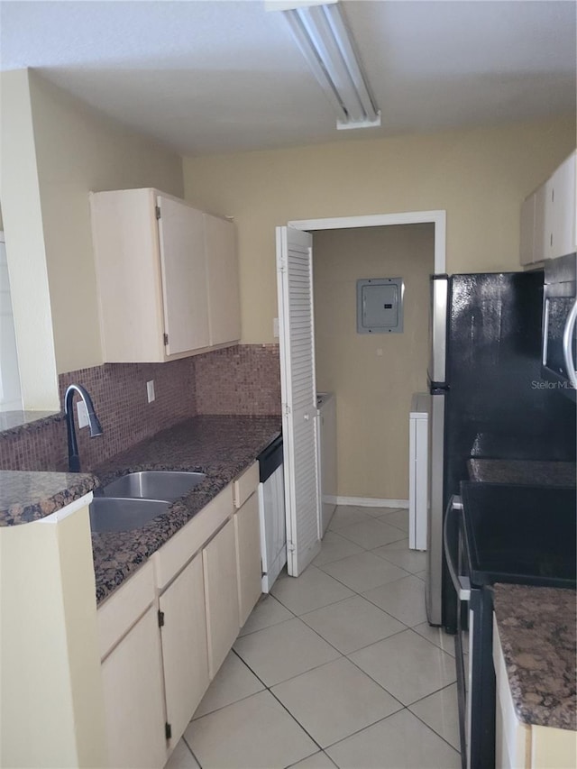 kitchen with stainless steel appliances, light tile patterned floors, sink, white cabinetry, and tasteful backsplash