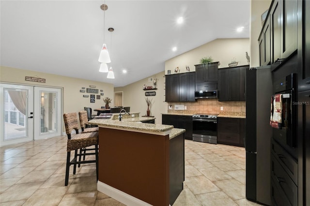 kitchen with hanging light fixtures, extractor fan, light stone countertops, an island with sink, and stainless steel electric range oven