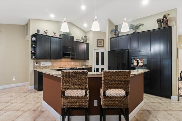 kitchen featuring black refrigerator, pendant lighting, light stone countertops, a kitchen island with sink, and backsplash