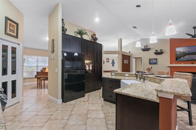 kitchen featuring sink, hanging light fixtures, a spacious island, a kitchen bar, and black fridge