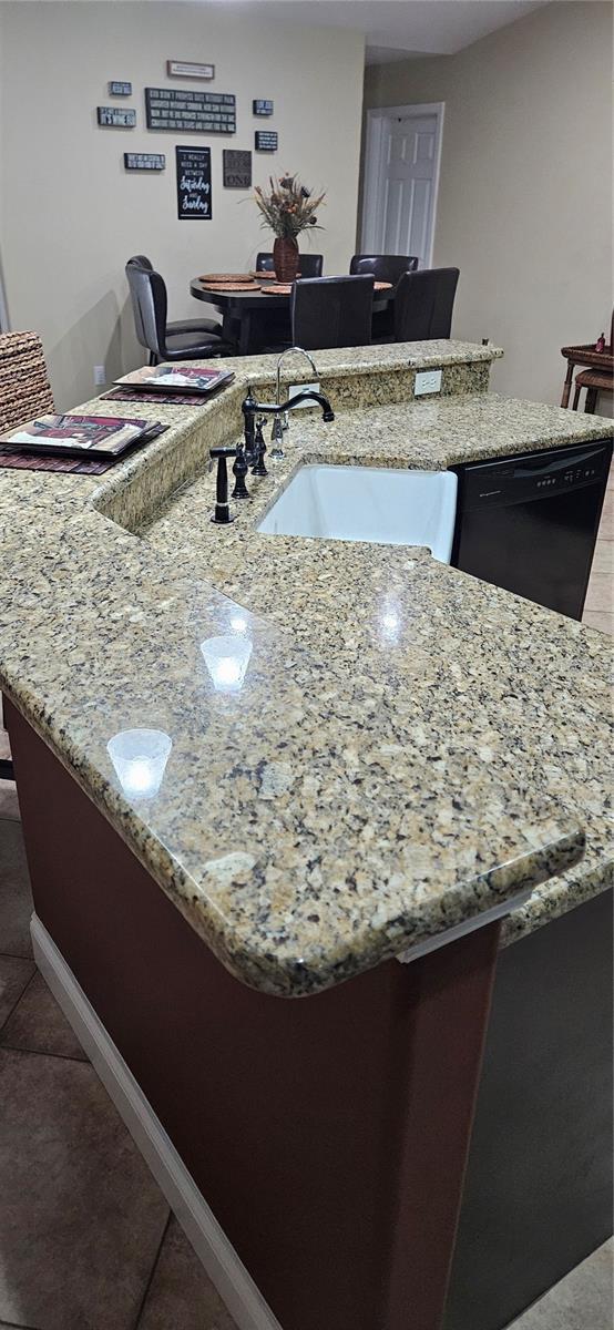 details featuring black dishwasher, sink, and light stone counters