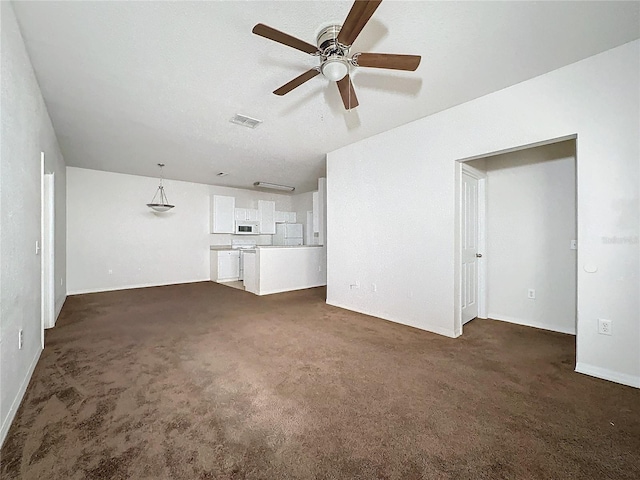 unfurnished living room featuring ceiling fan and dark colored carpet