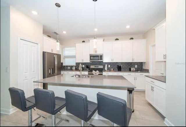 kitchen featuring stainless steel appliances, sink, pendant lighting, a center island with sink, and white cabinetry