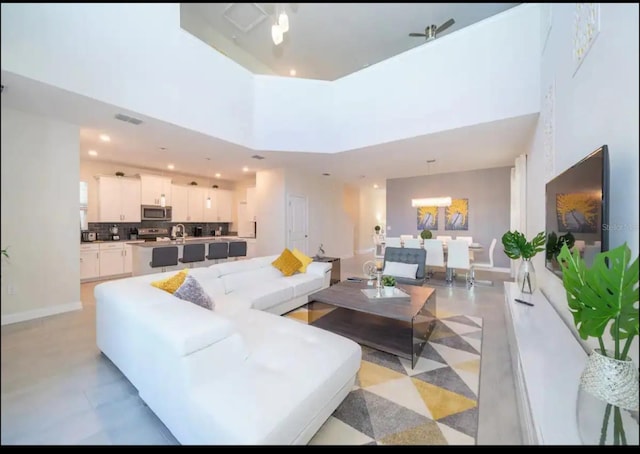 living room featuring a high ceiling, ceiling fan, and sink