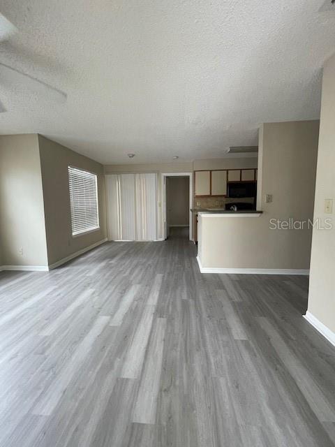 unfurnished living room with a textured ceiling and hardwood / wood-style floors