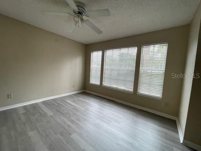 empty room with a textured ceiling, ceiling fan, and hardwood / wood-style flooring