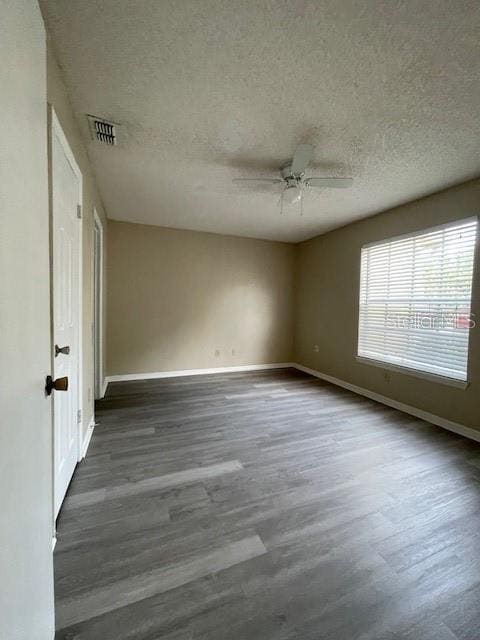 spare room featuring a textured ceiling, dark wood-type flooring, and ceiling fan