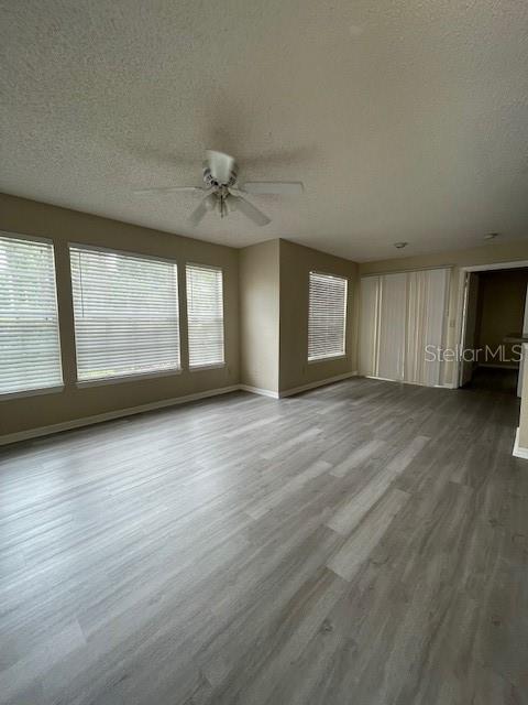 unfurnished living room with a textured ceiling, ceiling fan, and wood-type flooring