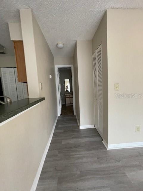 hall with a textured ceiling and dark wood-type flooring