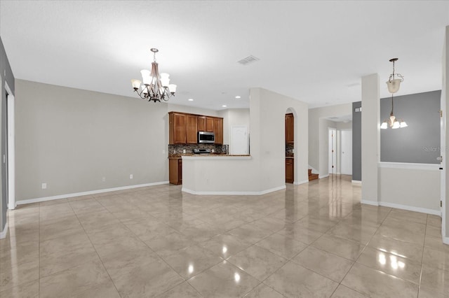 unfurnished living room featuring a chandelier, arched walkways, visible vents, and baseboards