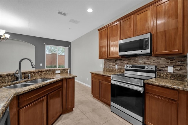 kitchen featuring appliances with stainless steel finishes, brown cabinetry, a sink, and tasteful backsplash