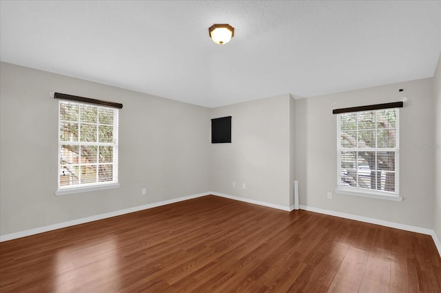 spare room featuring wood finished floors, a wealth of natural light, and baseboards