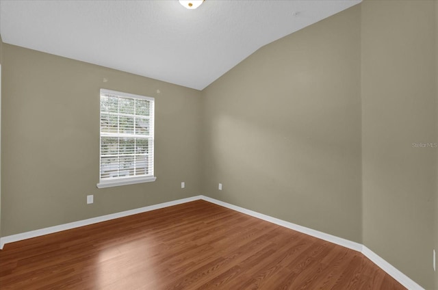 unfurnished room with vaulted ceiling, baseboards, and wood finished floors