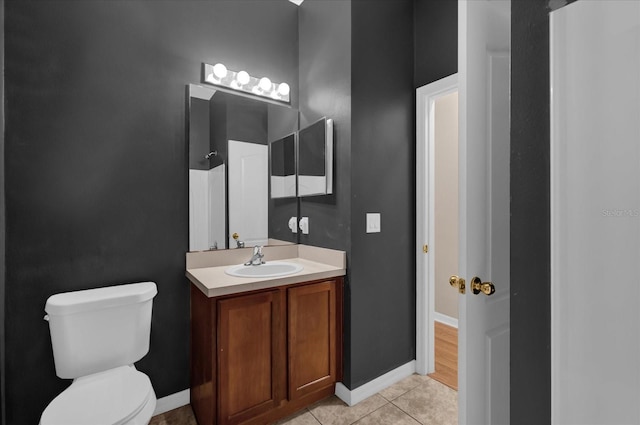 bathroom with toilet, vanity, baseboards, and tile patterned floors