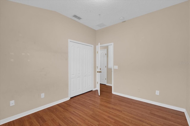 spare room with baseboards, a textured ceiling, visible vents, and wood finished floors