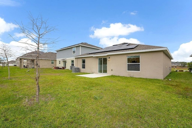 rear view of house featuring central AC, a yard, solar panels, and a patio