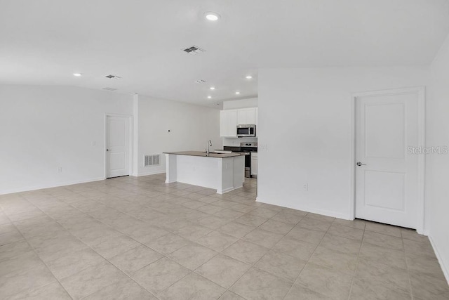 unfurnished living room with light tile patterned floors, lofted ceiling, and sink