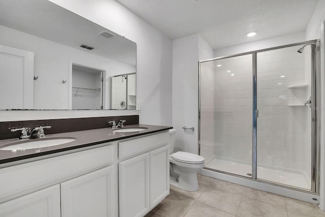 bathroom featuring an enclosed shower, vanity, tile patterned flooring, and toilet