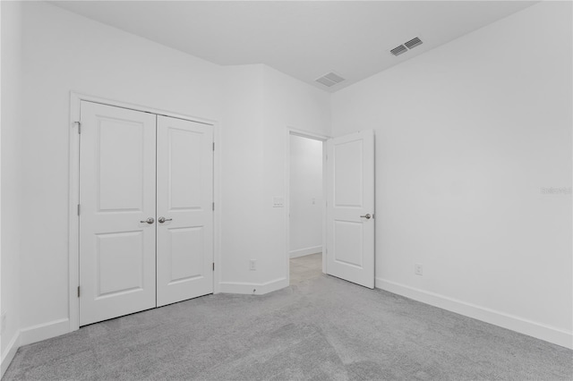 unfurnished bedroom featuring light colored carpet and a closet