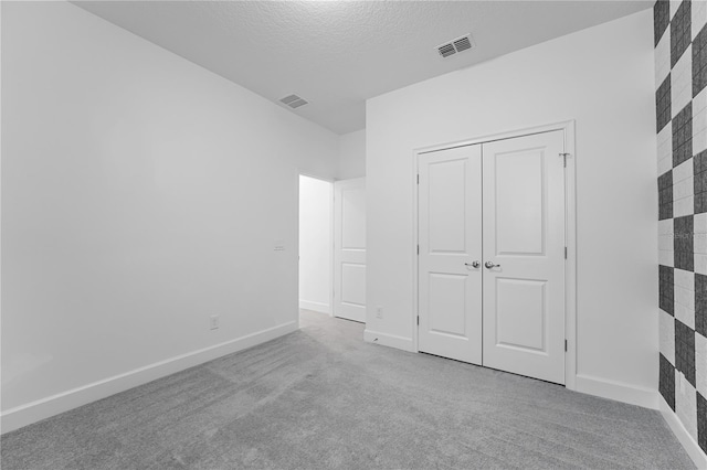 unfurnished bedroom featuring a closet, light carpet, and a textured ceiling