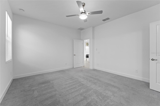 unfurnished room with ceiling fan, a healthy amount of sunlight, and light colored carpet