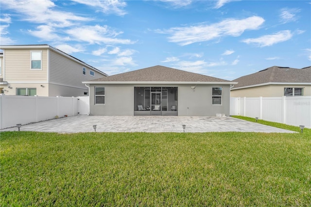 rear view of house featuring a patio area, a lawn, and a sunroom