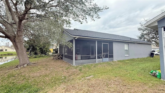 rear view of property featuring a water view, a sunroom, and a lawn