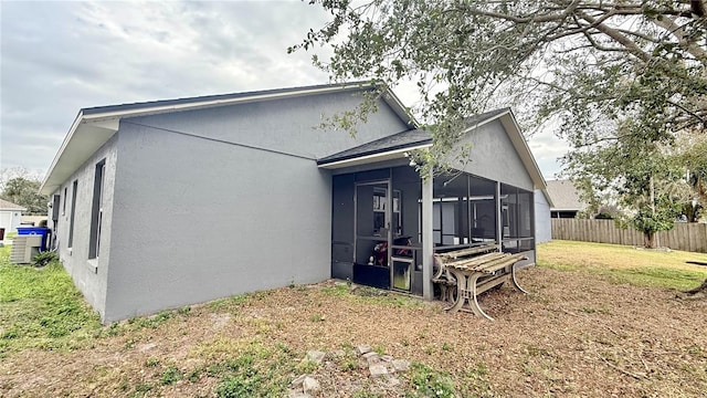 view of home's exterior featuring a yard, a sunroom, fence, and stucco siding