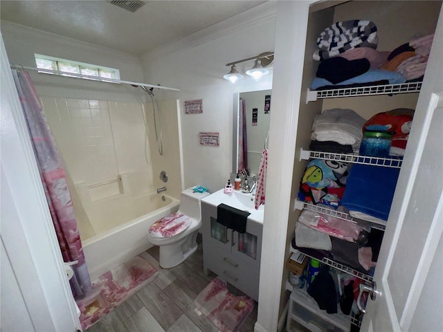 full bathroom featuring hardwood / wood-style floors, toilet, vanity, ornamental molding, and shower / bath combo