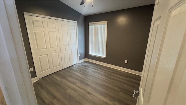 unfurnished bedroom with ceiling fan, a closet, dark wood finished floors, and baseboards