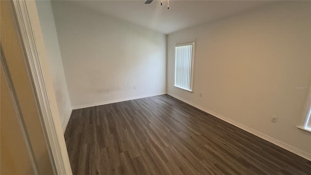 spare room with a healthy amount of sunlight, ceiling fan, baseboards, and dark wood-type flooring