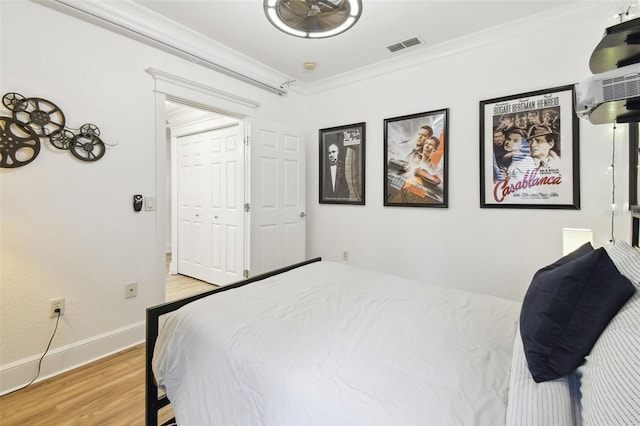 bedroom with a closet, crown molding, and light hardwood / wood-style floors