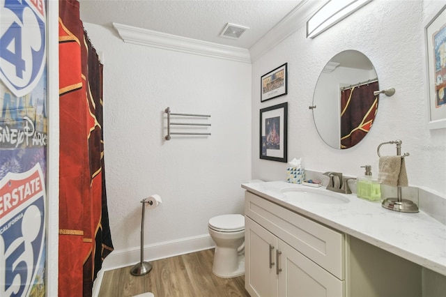 bathroom featuring toilet, vanity, wood-type flooring, crown molding, and a textured ceiling