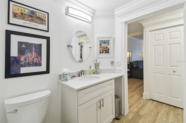 bathroom with toilet, vanity, crown molding, and hardwood / wood-style flooring