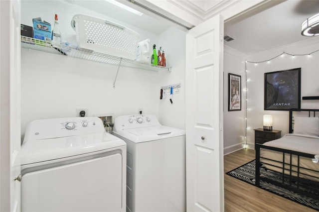 laundry room with hardwood / wood-style flooring, crown molding, and washing machine and dryer