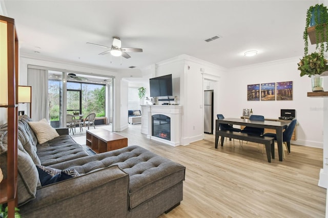 living room featuring ceiling fan, ornamental molding, and light hardwood / wood-style flooring