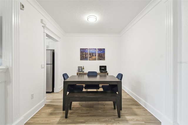 dining space featuring crown molding, a textured ceiling, and light hardwood / wood-style flooring