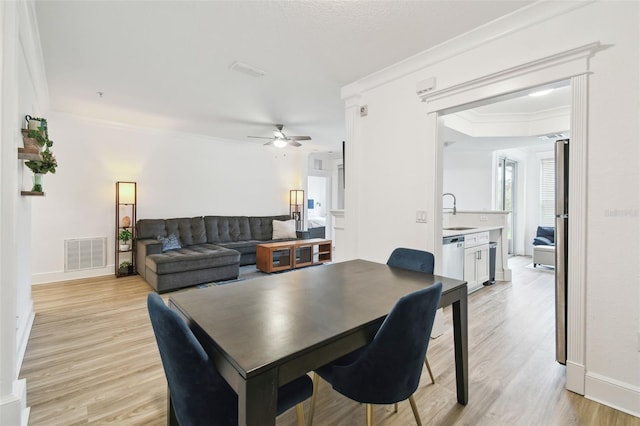 dining space featuring light hardwood / wood-style floors, sink, ornamental molding, and ceiling fan