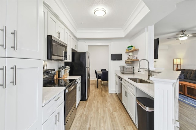 kitchen featuring white cabinets, stainless steel appliances, sink, light wood-type flooring, and crown molding