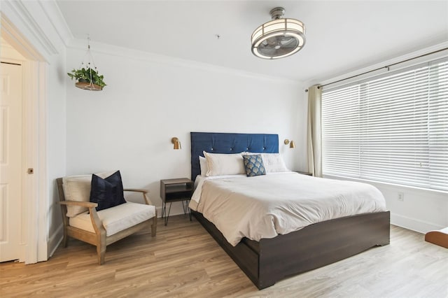 bedroom featuring multiple windows, light hardwood / wood-style flooring, and crown molding