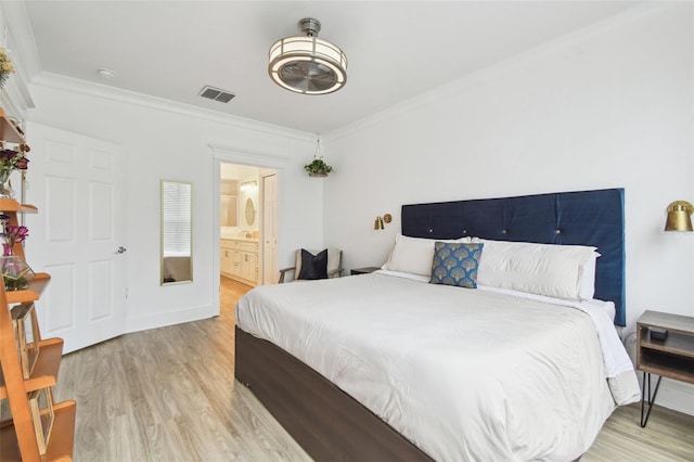 bedroom featuring light wood-type flooring, crown molding, and ensuite bath