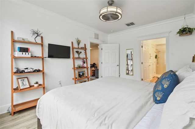 bedroom featuring ornamental molding, light hardwood / wood-style flooring, and ensuite bath