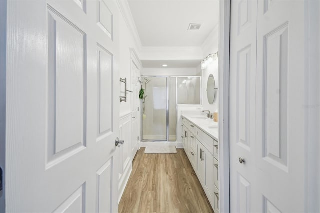 bathroom featuring vanity, ornamental molding, hardwood / wood-style flooring, and walk in shower