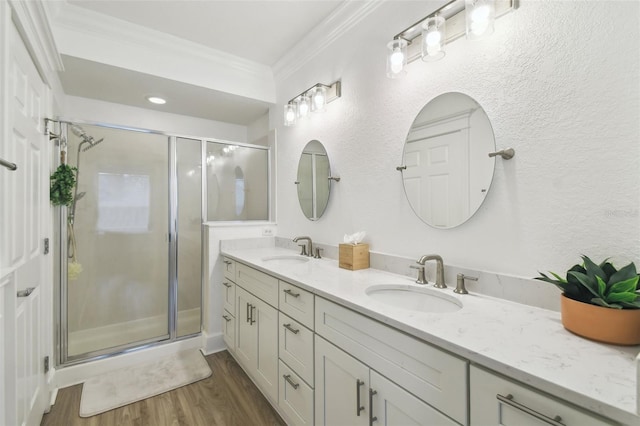 bathroom featuring a shower with shower door, hardwood / wood-style floors, vanity, and ornamental molding